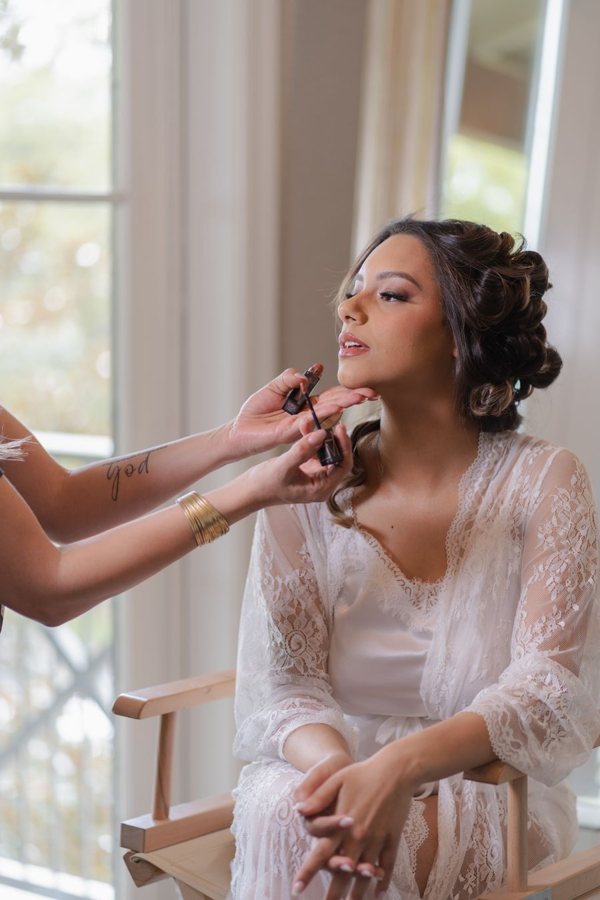 Bride having her makeup done by the window