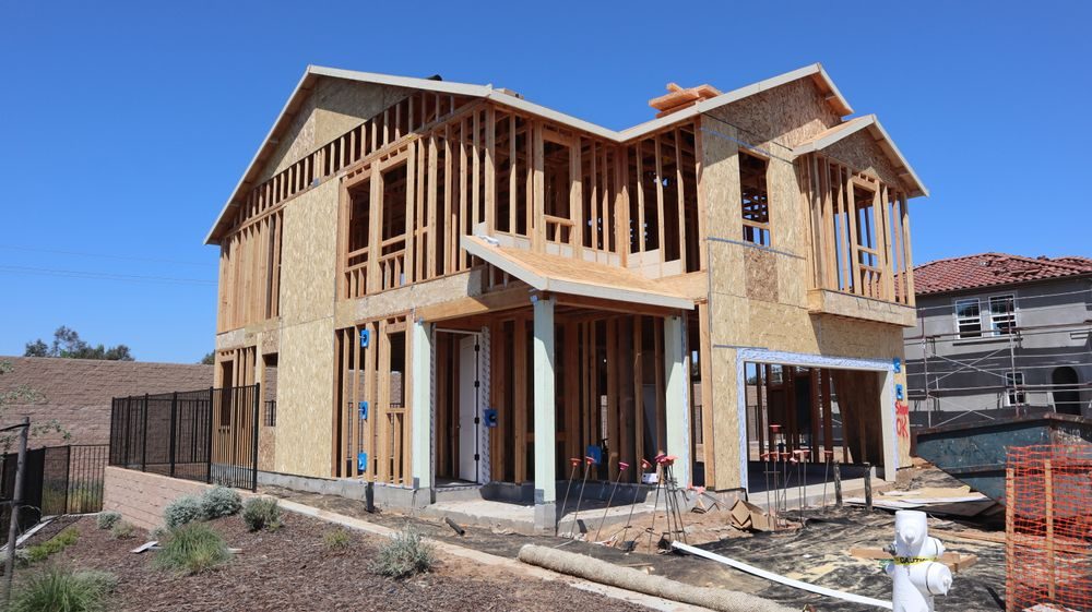 Two-story home in the framing stage under a blue Texas sky