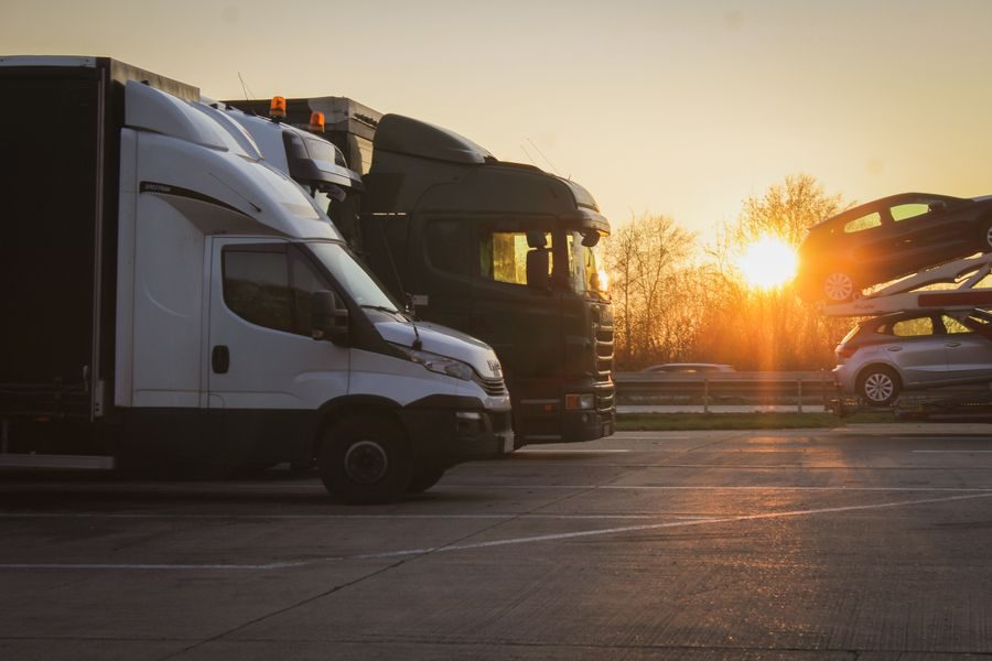 Lorries and vans parked at a depot at sunset