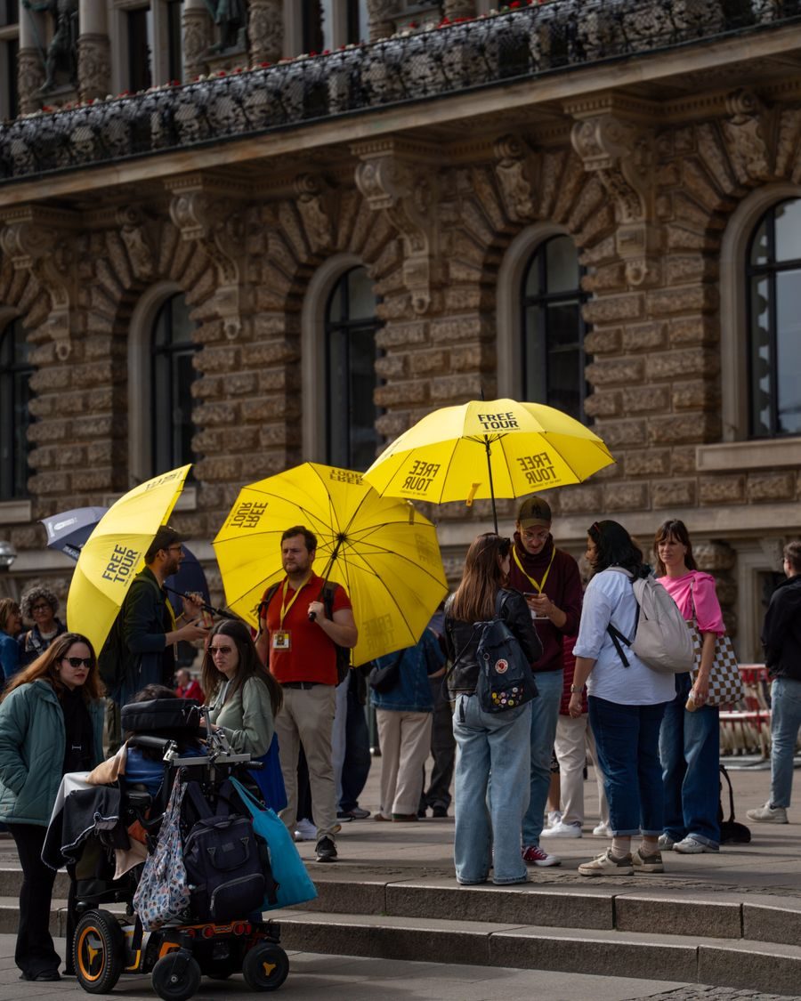 Tour group with yellow umbrellas in front of a historic building